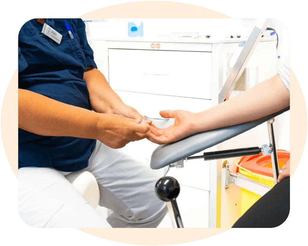 En diabetessköterska som tar ett blodprov från en patients finger